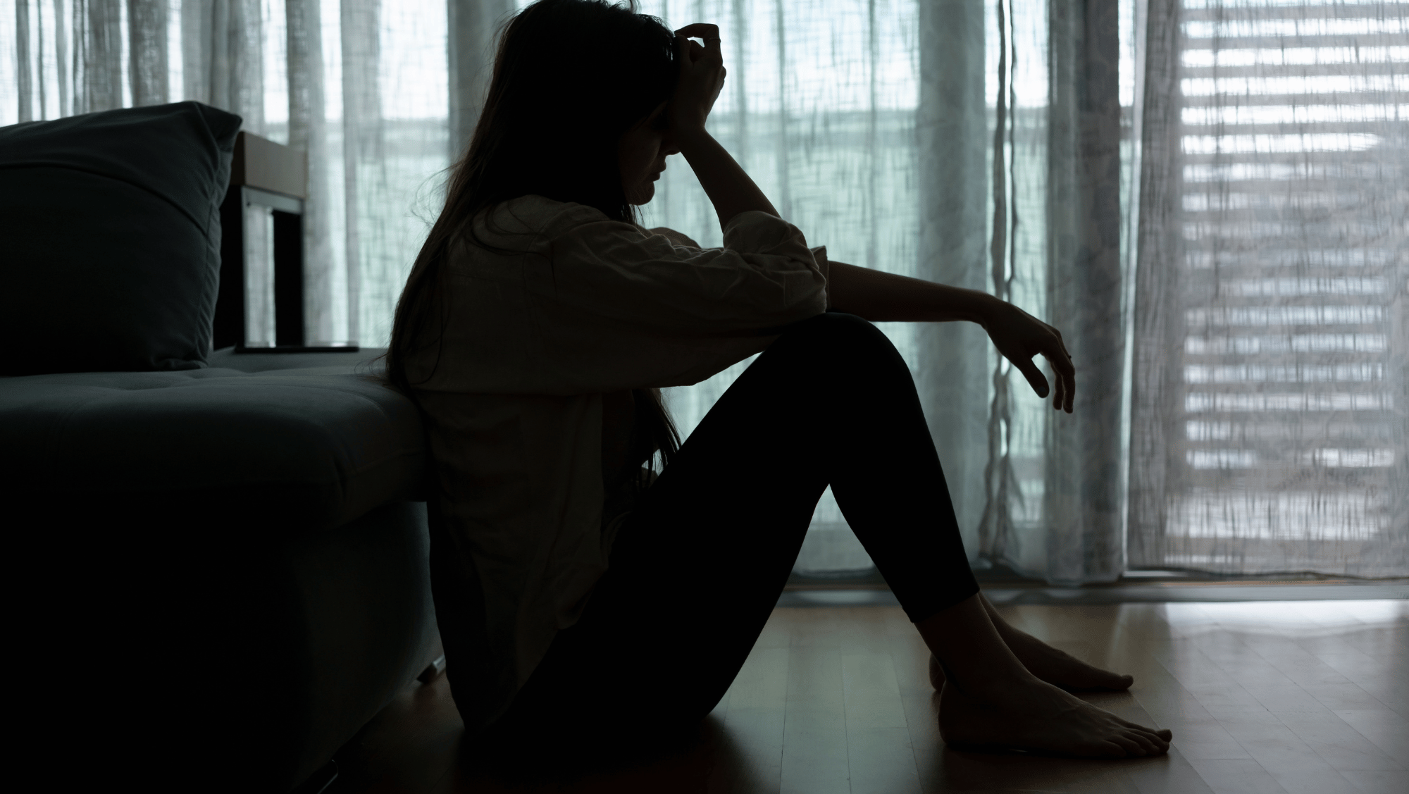 person sitting on floor with head in hands suffering from anxiety