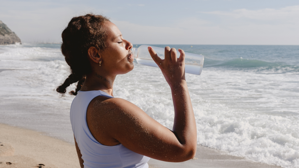 woman drinking water on the beach
