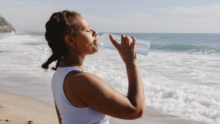woman drinking water on the beach