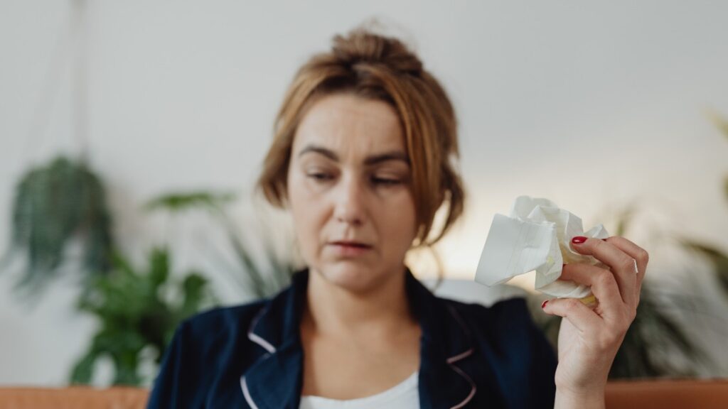 woman looking uneasy while crumbling a piece of paper